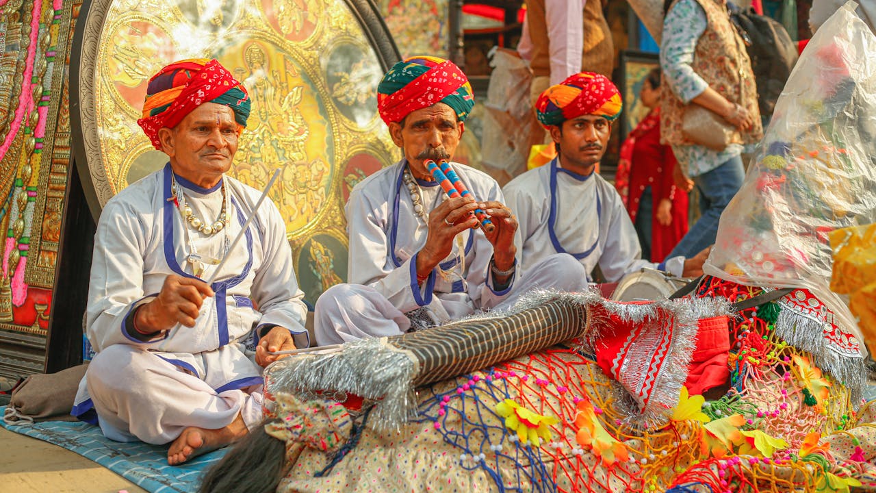 Indian men in traditional clothing playing musical instruments at a cultural festival.