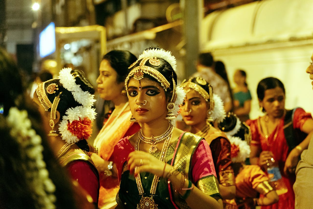 A vibrant street scene of Bharatanatyam dancers in traditional attire at night in Guruvayur, India.